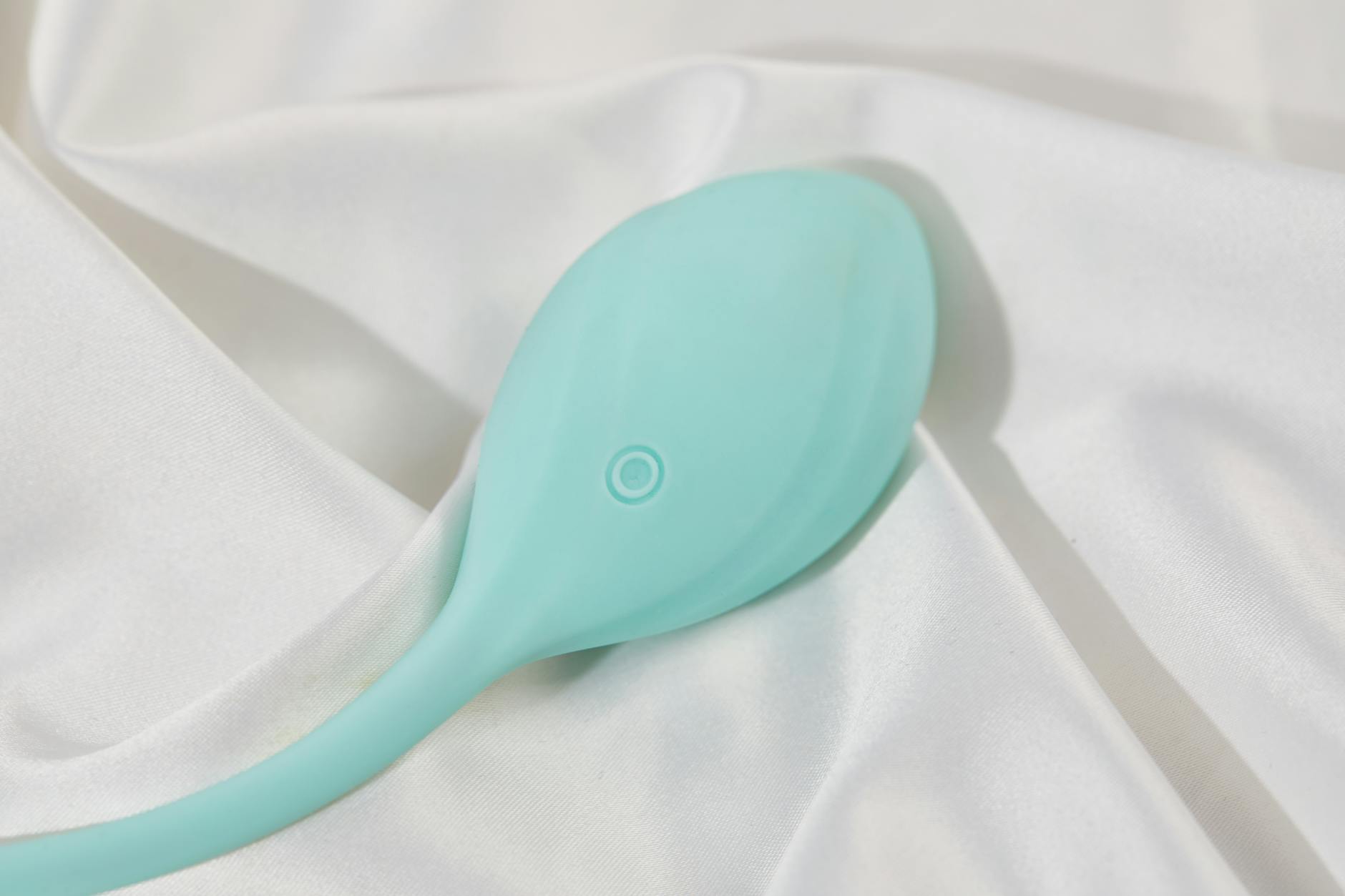 A sleek teal lemon vibrator on white silk fabric, symbolizing clean, intimate partnership moments