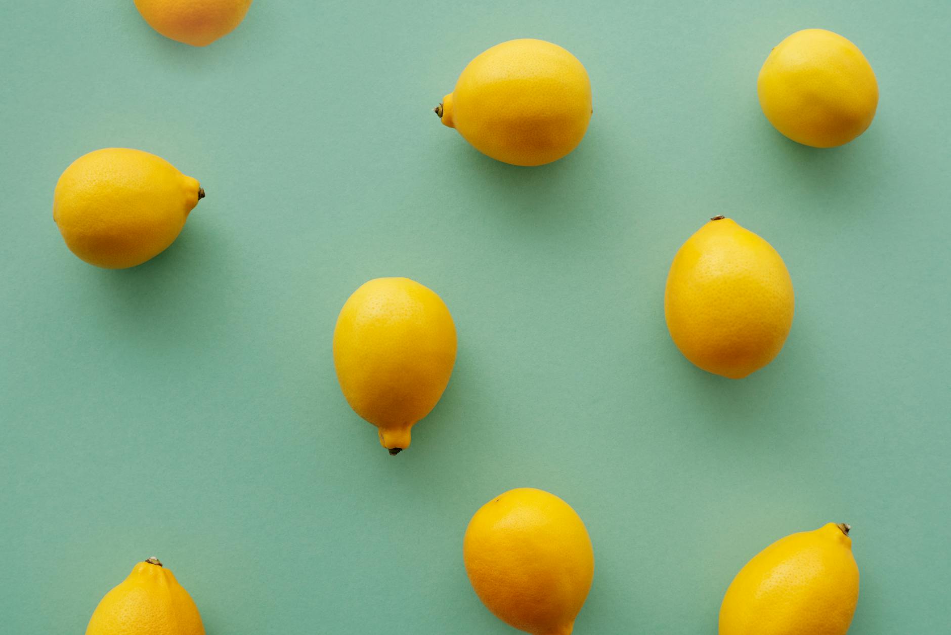 Bright yellow lemons arranged on a pastel green background, representing freshness and renewal