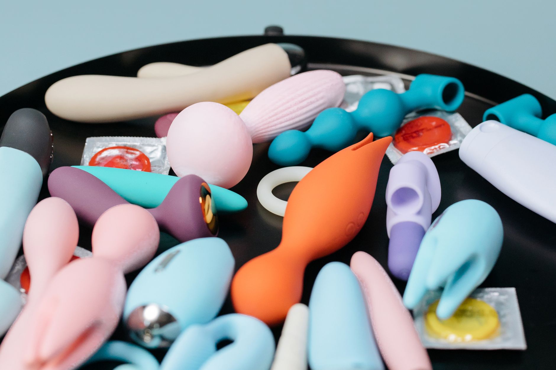A vibrant collection of various lemon vibrators and pleasure devices on a black tray, featuring diverse shapes and colors.