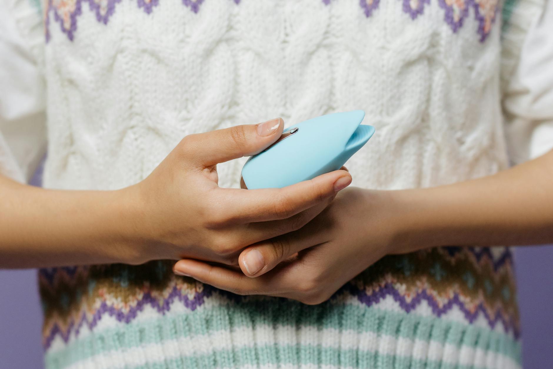 Close-up of hands holding a blue personal massager, demonstrating comfortable grip for sensitive use