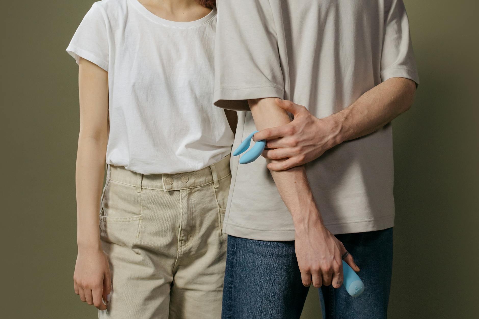 A couple standing together, exploring intimacy with a vibrator in a bedroom setting