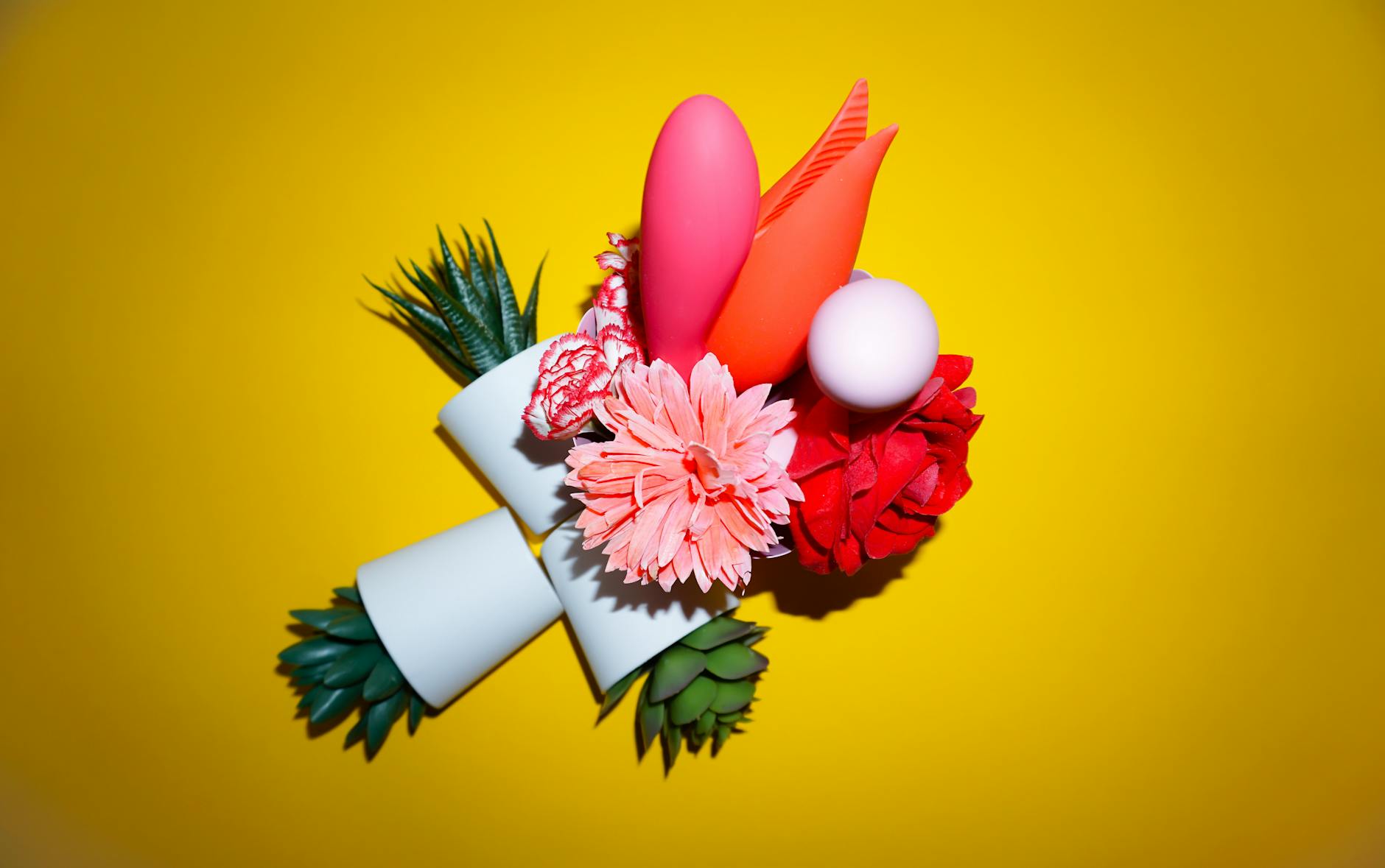 Colorful collection of vibrators and pleasure toys arranged on a bright yellow surface, showcasing varied designs and intensities.