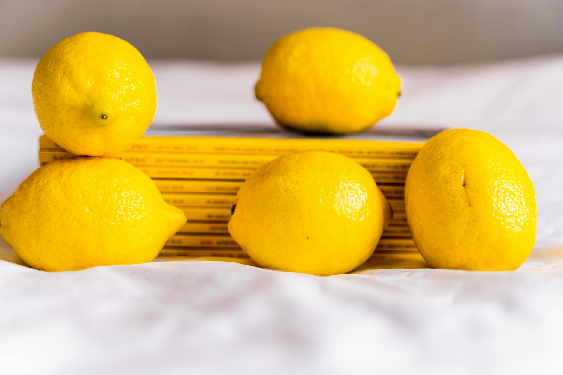 Fresh yellow lemons stacked with books on a white surface